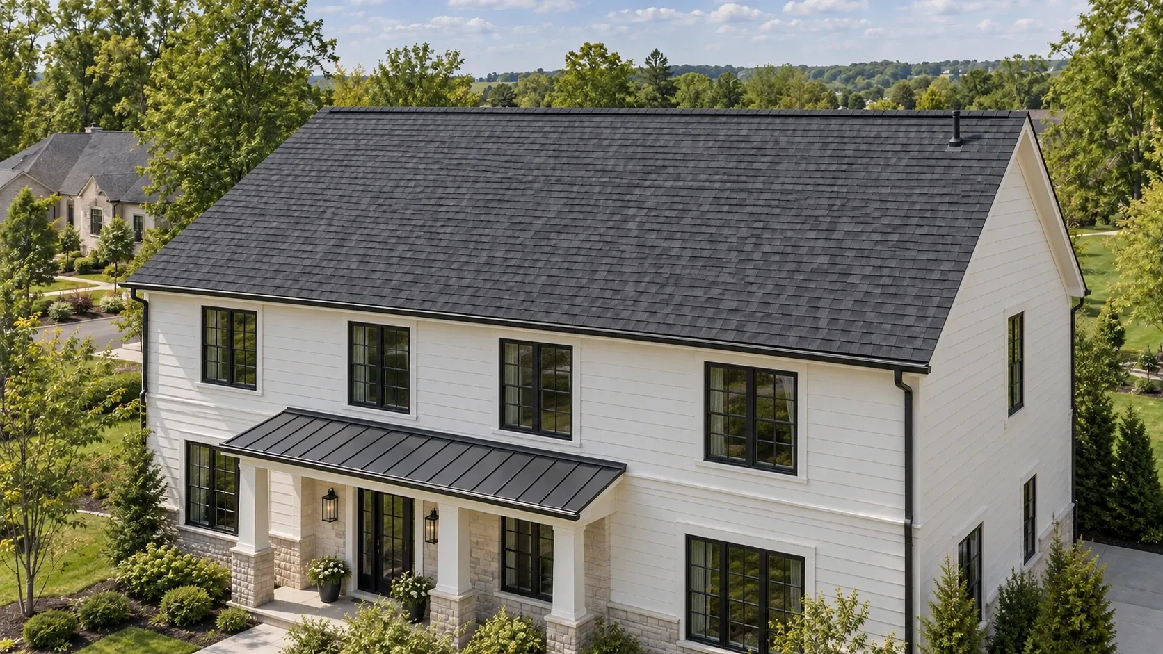 Pristine charcoal shingle roof on an upscale home with ivory siding, black windows, and stone accents in a leafy Midwest neighborhood