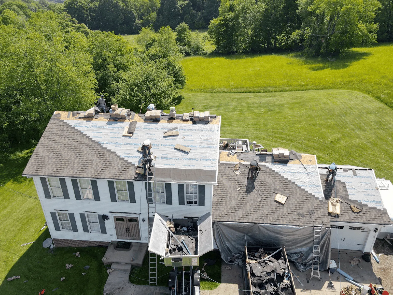 Aerial view of a HOF Roofing roof replacement job in progress with an Equipter protecting the property